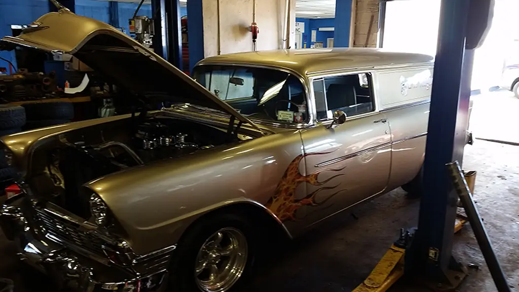 A classic wagon with a flame paint job up on a lift at Bailey Tire, hood open