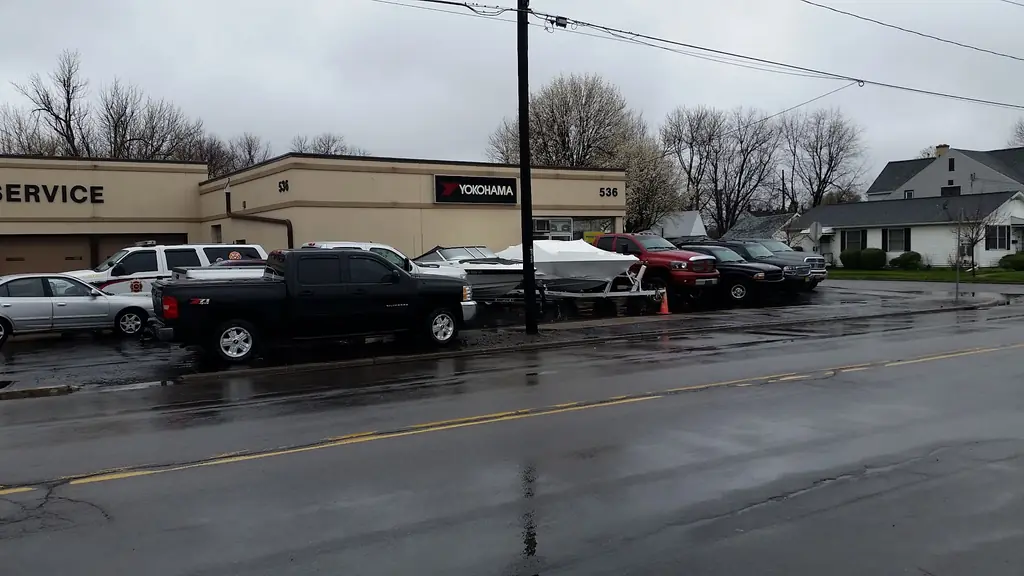 A boat on a trailer parked outside Bailey Tire Auto & Marine Service in Buffalo, with the shop's service signage behind it
